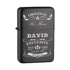 May include: Black metal lighter with a silver engraved design. The design includes the text "Original Hot Flame David Exclusive Est 1985 Quality 100% Premium".