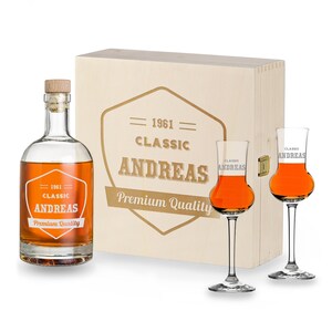 May include: A wooden box containing a bottle of liquor and two shot glasses. The box is engraved with the text "1961 Classic Andreas Premium Quality". The bottle and glasses are also engraved with the same text.