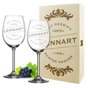 Może przedstawiać: Dwa przezroczyste szklane kieliszki do wina z wygrawerowanym tekstem "Gut Gereift EstD. Lennart 1970. Echter Genuss". Kieliszki znajdują się w drewnianym pudełku z złotym wzorem.
