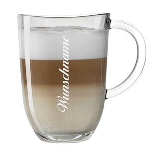 Pode incluir: Uma caneca de vidro transparente com alça, cheia de uma bebida de café em camadas. A bebida tem uma camada de espuma branca no topo, uma camada de café marrom no meio e uma camada de leite branco no fundo. A palavra "Wunschname" está impressa no lado da caneca.