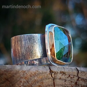 May include: A silver ring with a textured band and a large, faceted green gemstone set in a gold bezel.