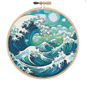 May include: A cross-stitch embroidery hoop with a colorful depiction of the Great Wave off Kanagawa, a famous Japanese woodblock print by Hokusai. The wave is rendered in shades of blue and green, with white foam and splashes.
