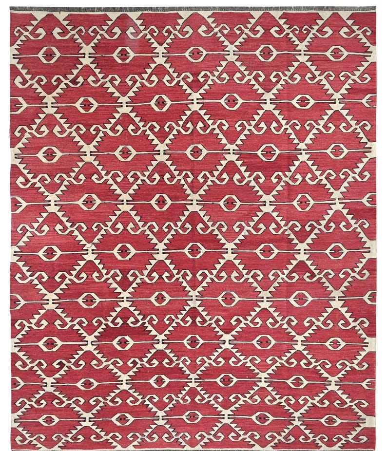Puede incluir: Una alfombra roja y blanca con un patr&oacute;n geom&eacute;trico de dise&ntilde;o tradicional. La alfombra tiene un patr&oacute;n repetitivo de remolinos y diamantes negros y blancos.