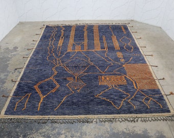May include: A blue and orange geometric patterned rug with fringe on all sides. The rug has a modern design with abstract shapes and lines.