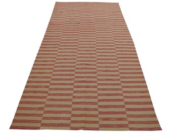 May include: A long, rectangular rug with a striped pattern in shades of red and beige. The stripes are horizontal and create a checkered effect.