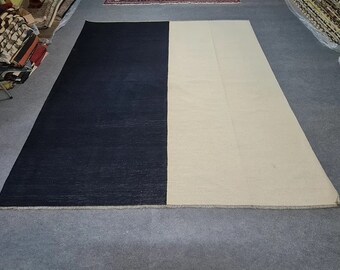 Puede incluir: Una alfombra rectangular grande con un llamativo diseño bicolor. Una mitad es azul marino oscuro y la otra es de color blanco roto cremoso. La alfombra tiene una estética sencilla y moderna, adecuada para varios estilos de interior.