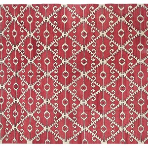 Puede incluir: Una alfombra roja y blanca con un patr&oacute;n geom&eacute;trico de dise&ntilde;o tradicional. La alfombra tiene un patr&oacute;n repetitivo de remolinos y diamantes blancos sobre un fondo rojo.
