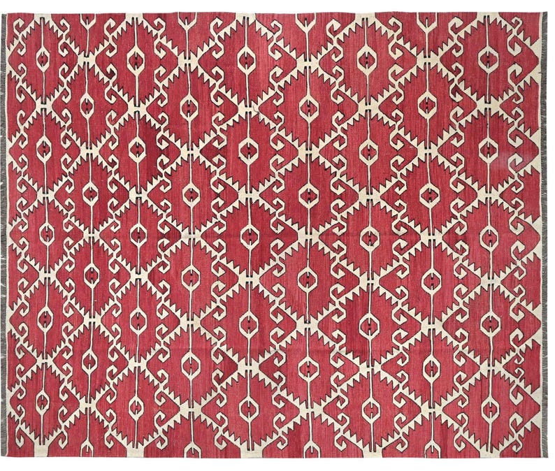 Puede incluir: Una alfombra roja y blanca con un patr&oacute;n geom&eacute;trico de dise&ntilde;o tradicional. La alfombra tiene un patr&oacute;n repetitivo de remolinos y diamantes blancos sobre un fondo rojo.
