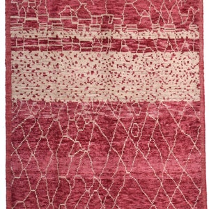 May include: A red and cream colored rug with a geometric pattern. The rug has a fringe border.