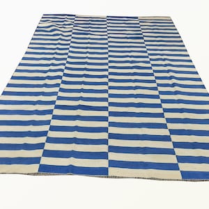 May include: Blue and white striped rug with a woven texture. The rug has a simple design with alternating blue and white stripes.