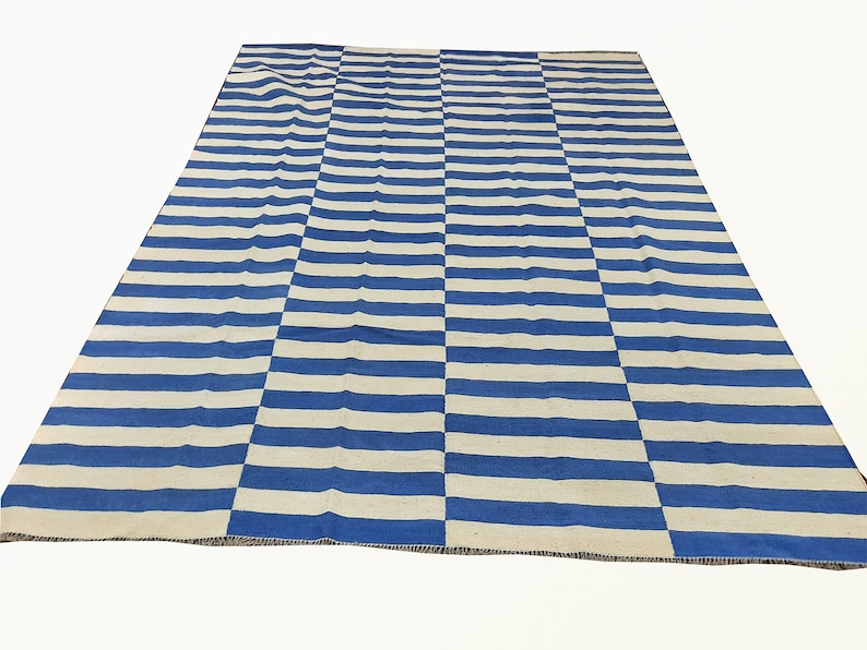 May include: Blue and white striped rug with a woven texture. The rug has a simple design with alternating blue and white stripes.