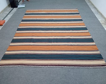 May include: A striped rug with brown, orange, teal, and white stripes. The rug has a fringe border.