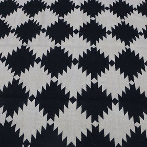 Puede incluir: Alfombra geom&eacute;trica con estampado en blanco y negro con un dise&ntilde;o en forma de diamante. La alfombra tiene un aspecto tejido texturizado.