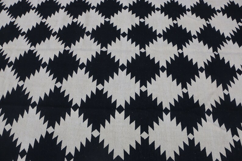 Puede incluir: Alfombra geom&eacute;trica con estampado en blanco y negro con un dise&ntilde;o en forma de diamante. La alfombra tiene un aspecto tejido texturizado.