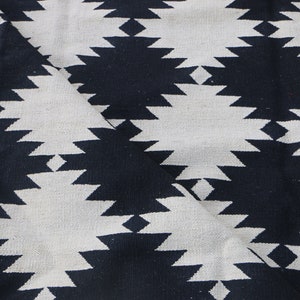 Puede incluir: Tela con estampado geom&eacute;trico en blanco y negro con un patr&oacute;n de rombos. La tela est&aacute; doblada por la mitad, mostrando el patr&oacute;n en ambos lados.