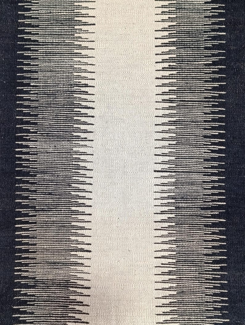 May include: Black and white striped rug with a textured woven design. The rug has a central white stripe with black stripes on either side.