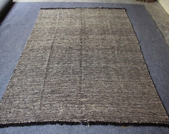 May include: A black and white woven rug with a fringed edge. The rug has a textured, hand-woven look.