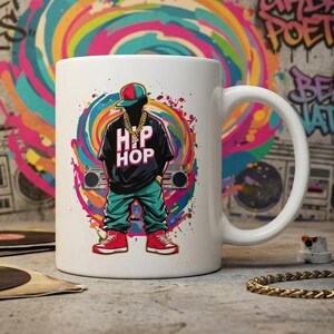 Könnte beinhalten: Ein weißer Keramikbecher mit einer bunten Grafik einer Figur, die eine Kappe, ein schwarzes T-Shirt mit dem Text HIP HOP, eine Goldkette, eine blaugrüne Hose und rote Turnschuhe trägt, vor einem lebendigen, wirbelnden, mehrfarbigen Hintergrund.