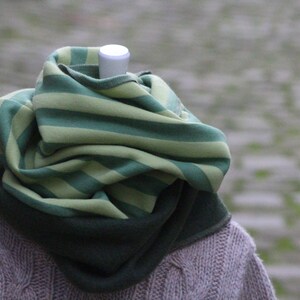 Könnte beinhalten: Ein grün- und hellgrüner gestreifter Schal mit dunkelgrünem Futter. Der Schal ist gefaltet und über einen braunen Pullover gelegt.