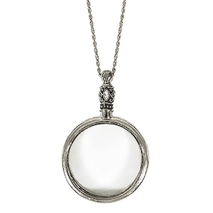 May include: Antique rhodium-plated magnifying glass pendant necklace. The pendant features a circular magnifying glass with a decorative bezel and a detailed bail. The chain is a delicate silver-tone rope style. The text "Antique Rhodium" is at the bottom.