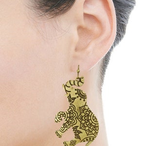 May include: Gold tone dangle earrings featuring an elephant design with intricate mandala patterns.