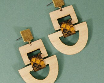 Peut inclure: Une paire de boucles d'oreilles en bois avec des formes géométriques et un accent à motif brun et or. Les boucles d'oreilles sont en bois clair et ont un design moderne.