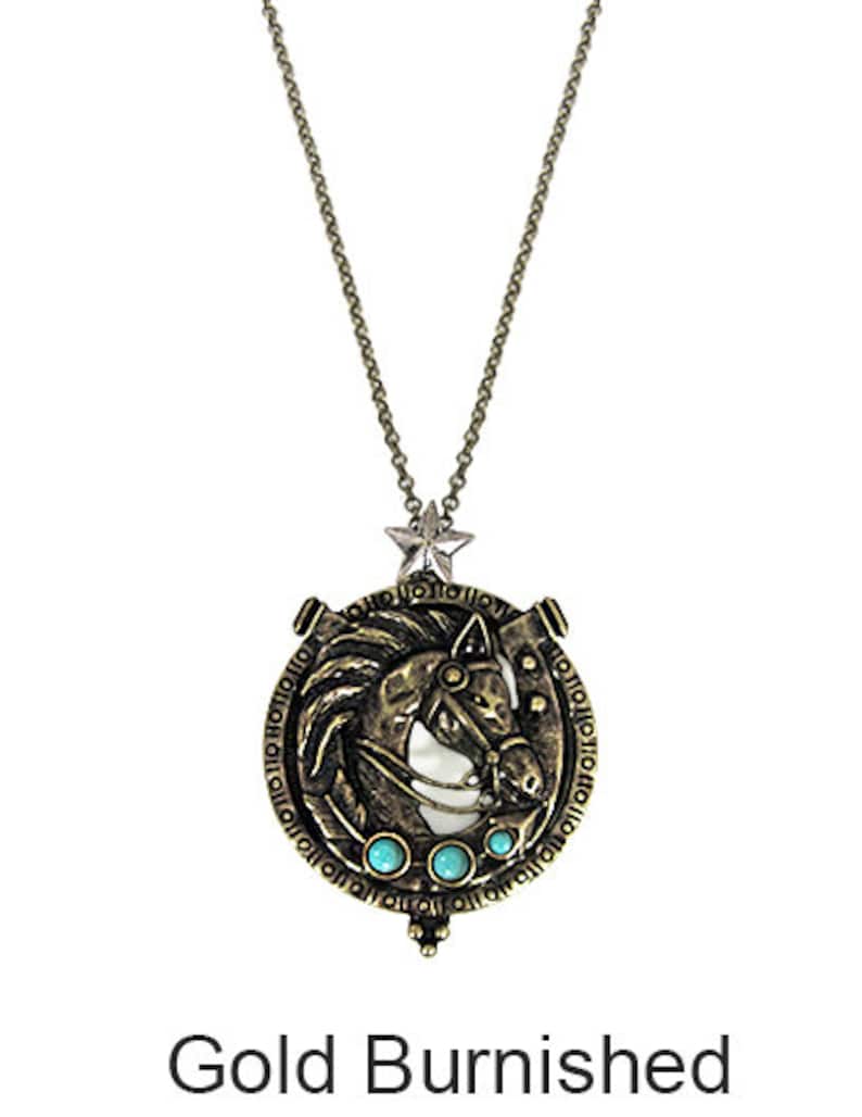 May include: Gold-toned necklace with a round pendant featuring a horse head design with turquoise accents. The pendant has a star charm at the top and is surrounded by a circular inscription.