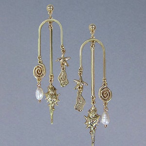 May include: Gold dangle earrings with a seashell, starfish, and pearl accents. The earrings are suspended from a thin gold bar.