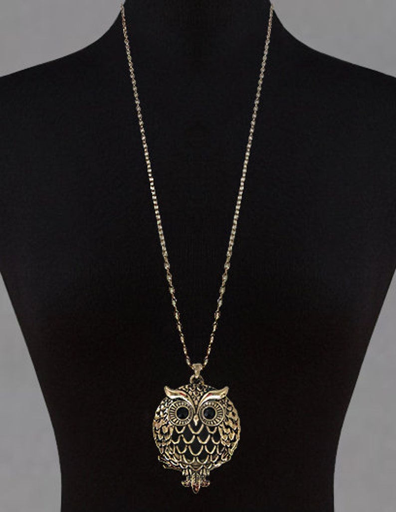 Peut inclure: Un collier en cha&icirc;ne dor&eacute;e avec un pendentif en forme de hibou. Le hibou est d&eacute;taill&eacute; avec des yeux noirs et un corps textur&eacute;.