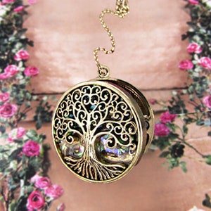 Può includere: Collana in tono oro con un ciondolo rotondo che presenta un design dettagliato dell'albero della vita. Il ciondolo ha un'intarsio di madreperla di abalone iridescente.