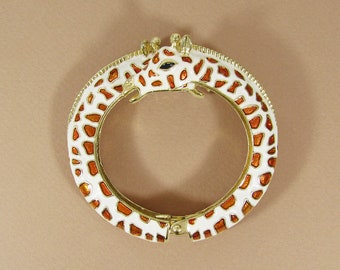 May include: A gold-tone bangle bracelet with a white and orange enamel giraffe design.