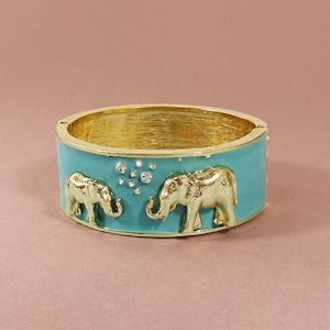 May include: A turquoise enamel bangle bracelet with a gold-tone finish features two gold elephant figures and a cluster of clear rhinestones.