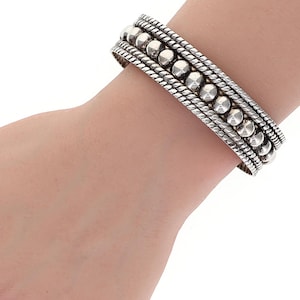 May include: A silver bracelet with a beaded and rope design.