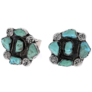 May include: A pair of silver earrings with turquoise stones set in a flower-like design.