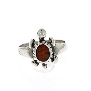May include: A silver ring with a turtle design. The turtle's shell is made of red coral.