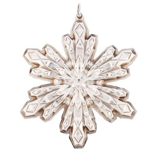 May include: A silver snowflake ornament with a detailed, intricate design. The snowflake is made of metal and has a shiny finish.