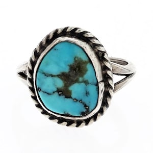 May include: A silver ring with a turquoise stone set in a rope-like border. The ring has a simple band.