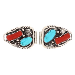 May include: A pair of silver watch band clasps with turquoise and coral inlay. The clasps are intricately detailed with a southwestern design.
