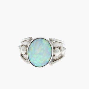 May include: A silver ring with an oval opal gemstone. The ring has a beaded design on the band.