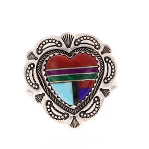 May include: A silver heart-shaped ring with a multi-coloured stone inlay. The stone is a mix of red, green, blue, purple, and black.