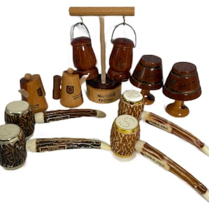 May include: A collection of vintage wooden salt and pepper shakers and other decorative items. The collection includes barrel-shaped shakers, a teapot, and a well-shaped holder. Some items have text that reads "Muir Woods California", "Pueblo, Colo", and "Illinois Home of Abe Lincoln".