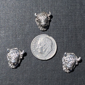 May include: Three silver buffalo head charms, each about the size of a UK ten pence coin.