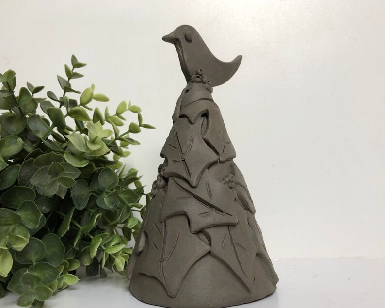 Op de afbeelding: Een bruine keramische kerstboomversiering met een vogel erop. De boom is versierd met bladeren en de vogel heeft een eenvoudig ontwerp.