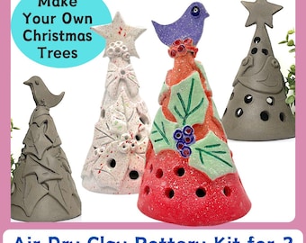 Op de afbeelding: Vier air dry klei kerstboom pottenbakkits in verschillende kleuren, waaronder grijs, wit en rood. De bomen hebben vogel- en sterrenopzetstukken. De tekst "Make Your Own Christmas Trees" staat in een blauwe cirkel. De tekst "Air Dry Clay Pottery Kit for 2" staat eronder.