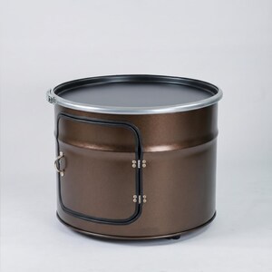 Puede incluir: Una unidad de almacenamiento cil&iacute;ndrica de metal con acabado en color bronce met&aacute;lico. Presenta una parte superior plana negra bordeada por una banda de metal plateado y una puerta lateral rectangular con un peque&ntilde;o tirador plateado y bisagras.