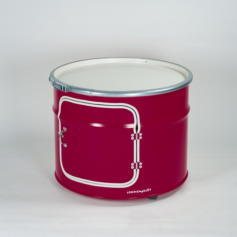 Puede incluir: Un mueble cil&iacute;ndrico de metal color magenta con una parte superior plana blanca y un borde de metal plateado. El frente presenta una puerta rectangular delineada en blanco con un peque&ntilde;o tirador y bisagras plateadas. La palabra LOCKENGELOT est&aacute; impresa en blanco en la base.