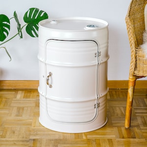 Puede incluir: Barril de metal blanco con una puerta y un asa. El barril se utiliza como mesa auxiliar.