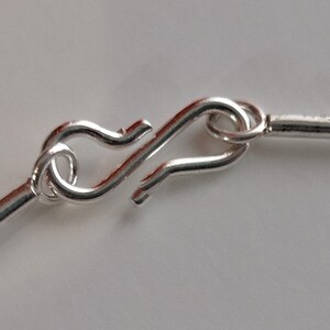 May include: Close-up of a silver clasp on a silver cable chain necklace.