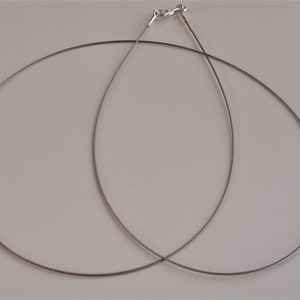 May include: Two silver-toned cable chains, each with a clasp, are lying on a white surface.
