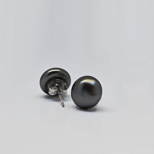 Può includere: Un paio di orecchini a bottone di perla nera con perni d'argento.